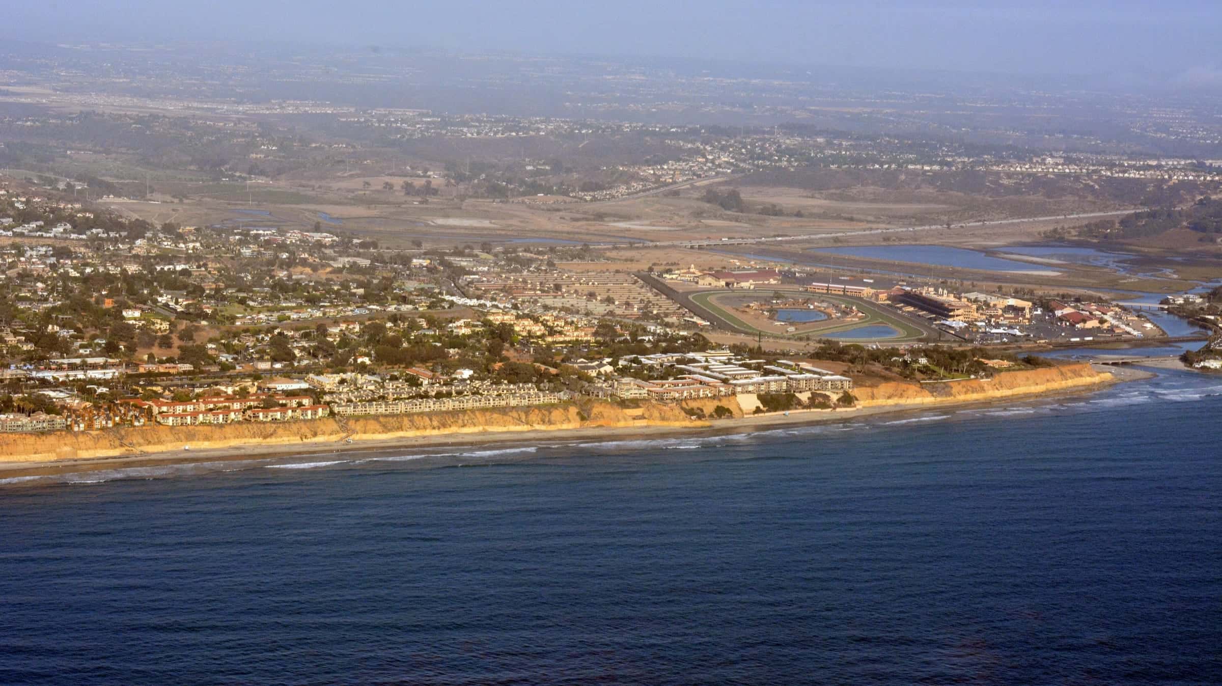 Aerial view of the coast at Del Mar and Solana Beach, with bluff-top homes, the fairgrounds racetrack and the San Dieguito Lagoon