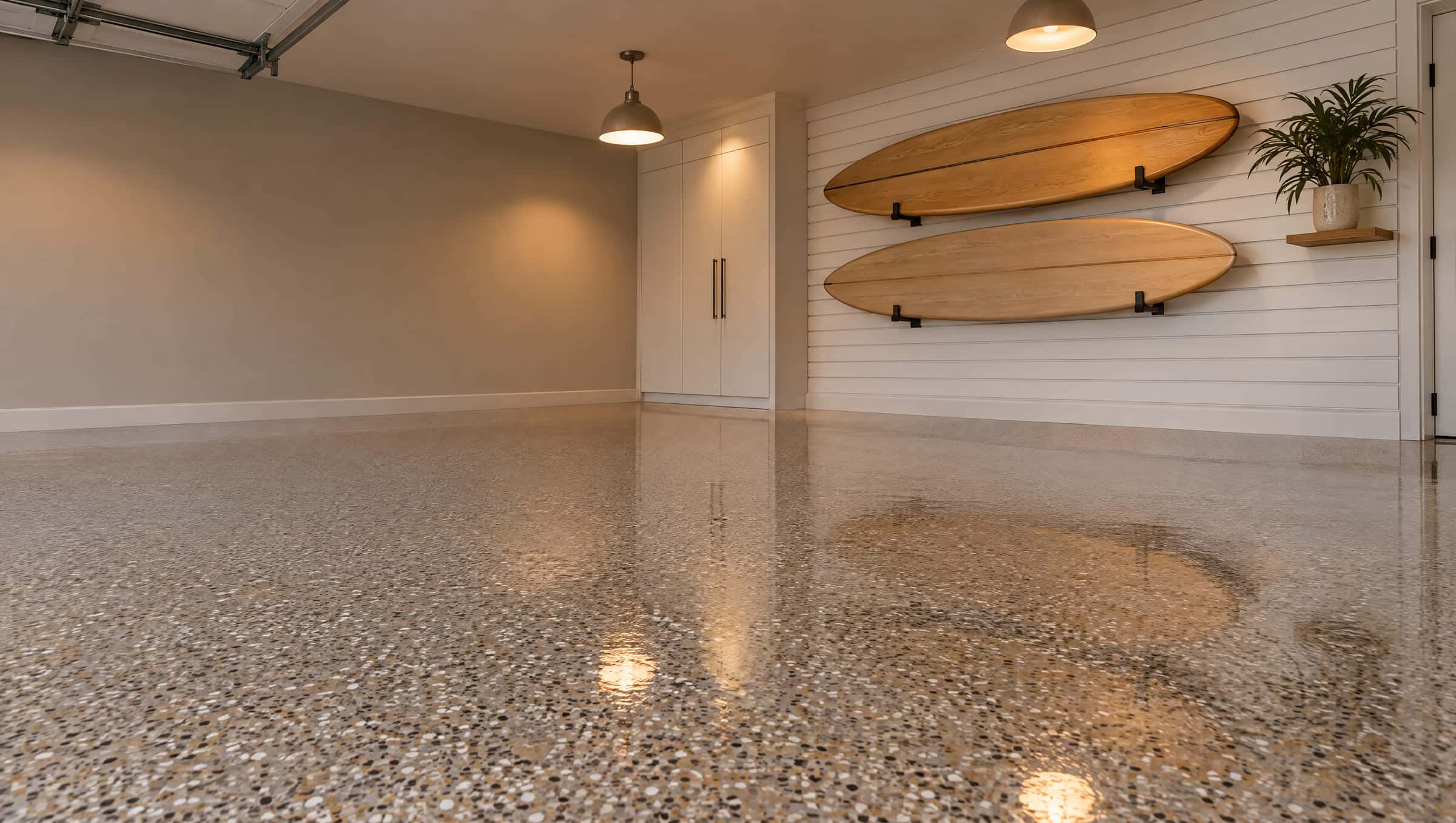 Coastal-modern garage with a warm-gray, white and tan flake epoxy floor and surfboards on the wall