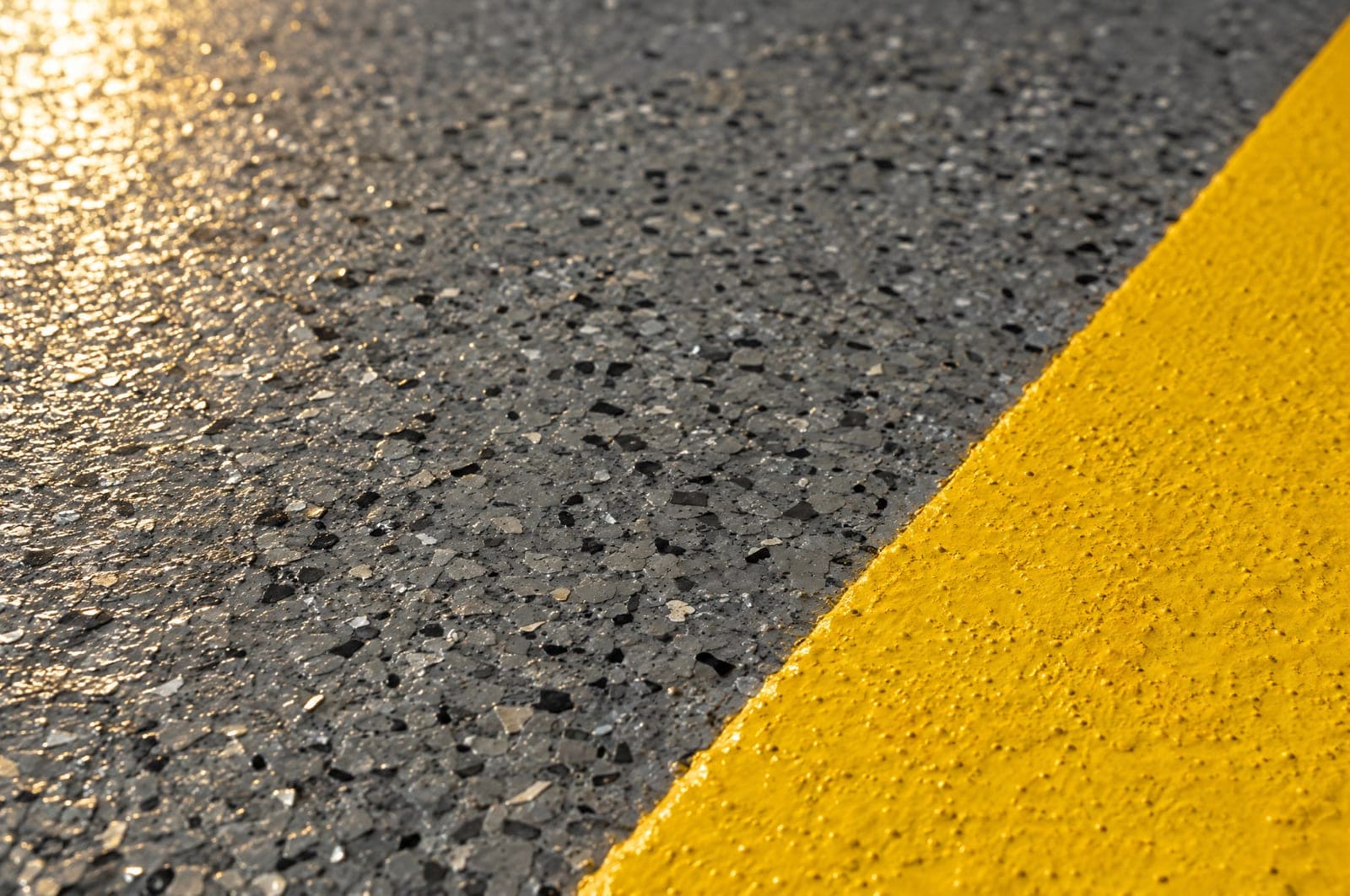 Close-up of a gray quartz-broadcast epoxy texture meeting a safety-yellow line